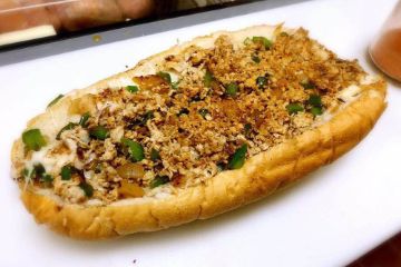 Cheesesteak hoagie topped with peppers and seasoning