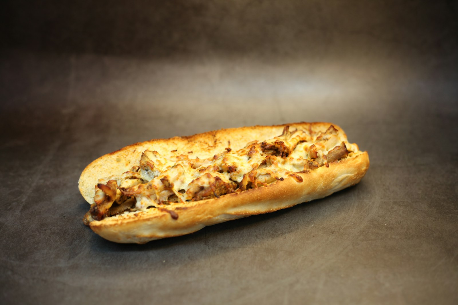 Chopped chicken and melted cheese filling a long roll