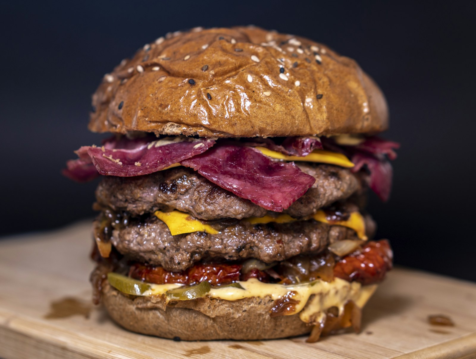 A stacked burger with bacon on a toasted bun