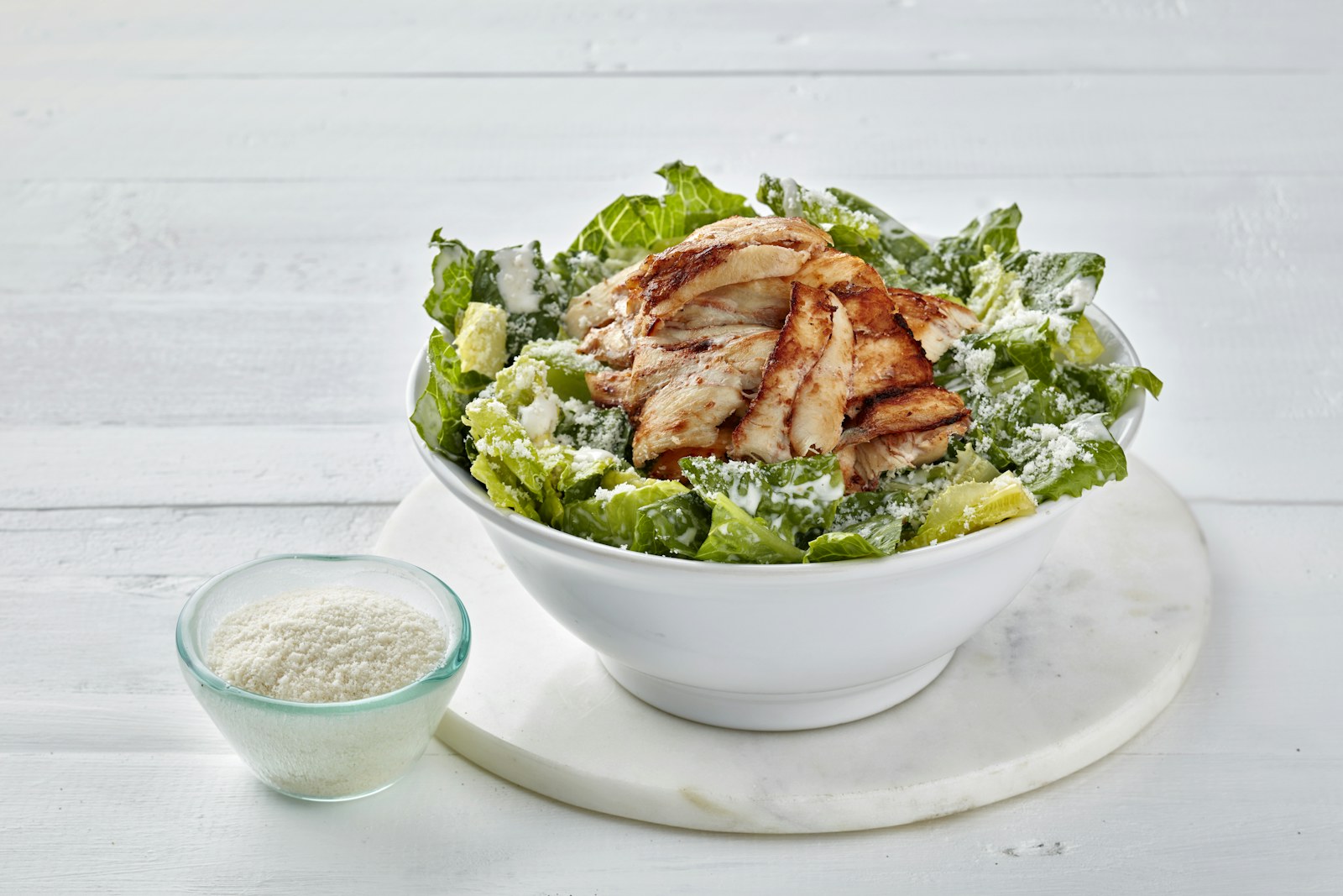 Grilled chicken caesar salad in a white bowl