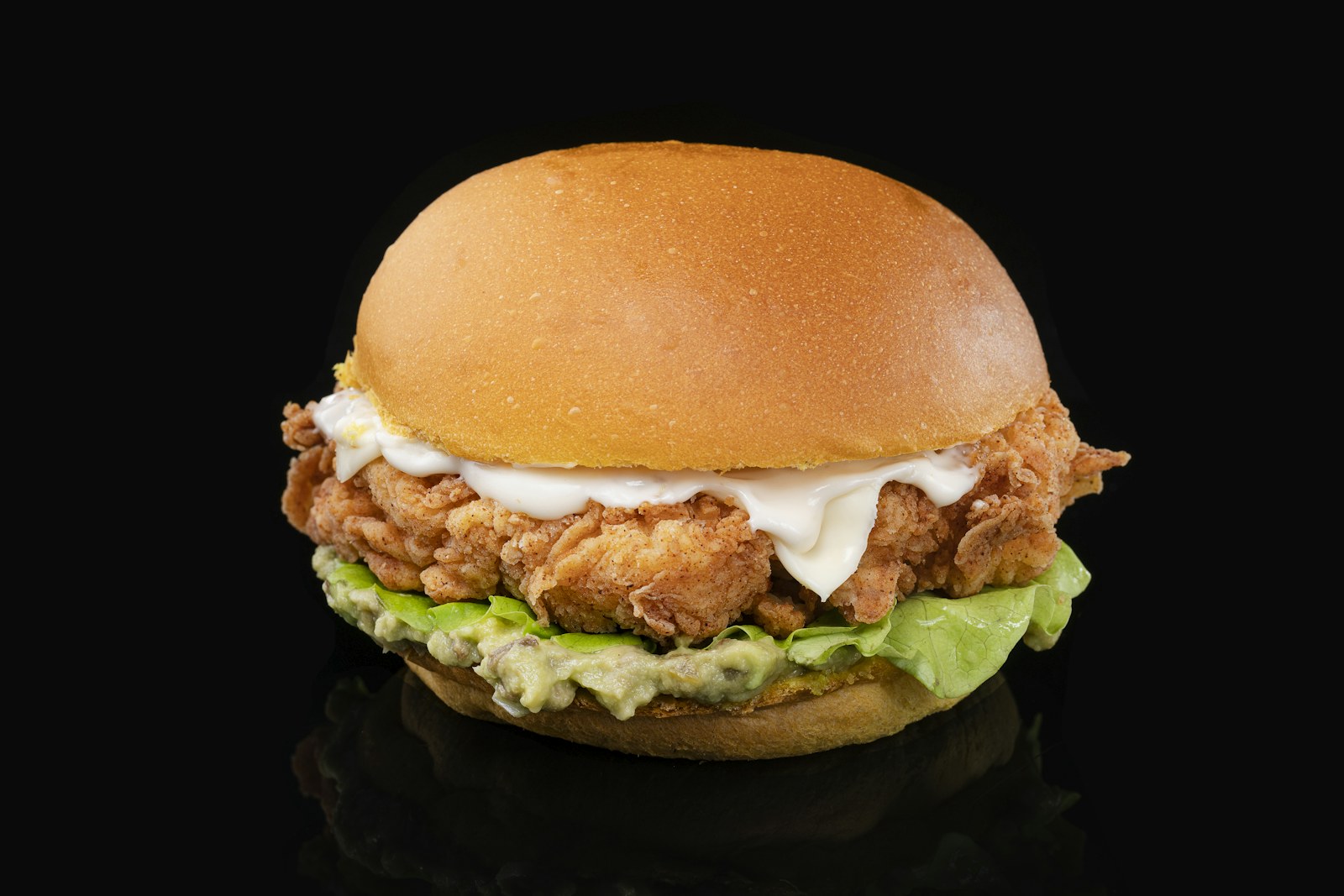 Crispy chicken sandwich with sauce and lettuce on a bun