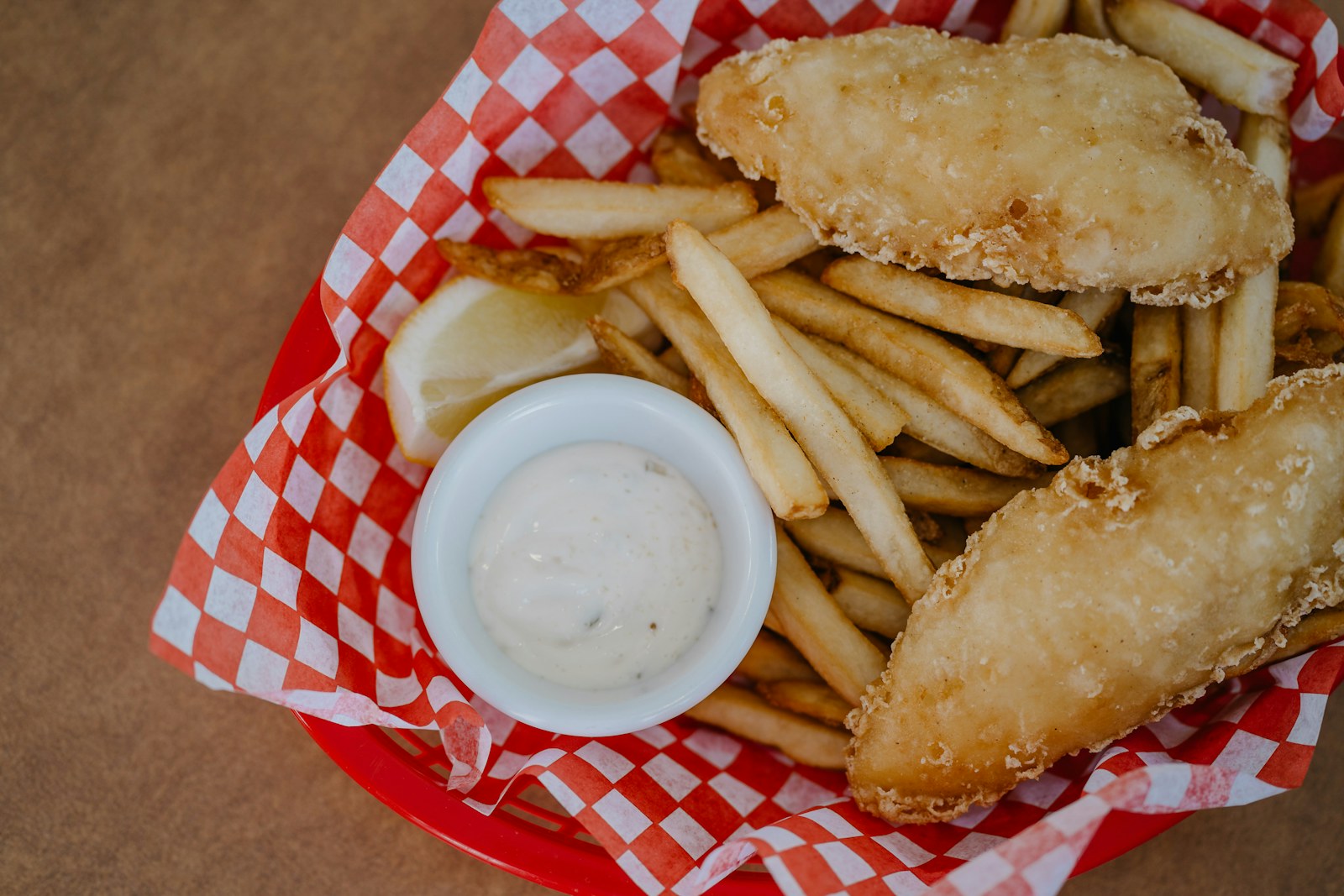 Fried fish pieces with fries and a cup of tartar sauce