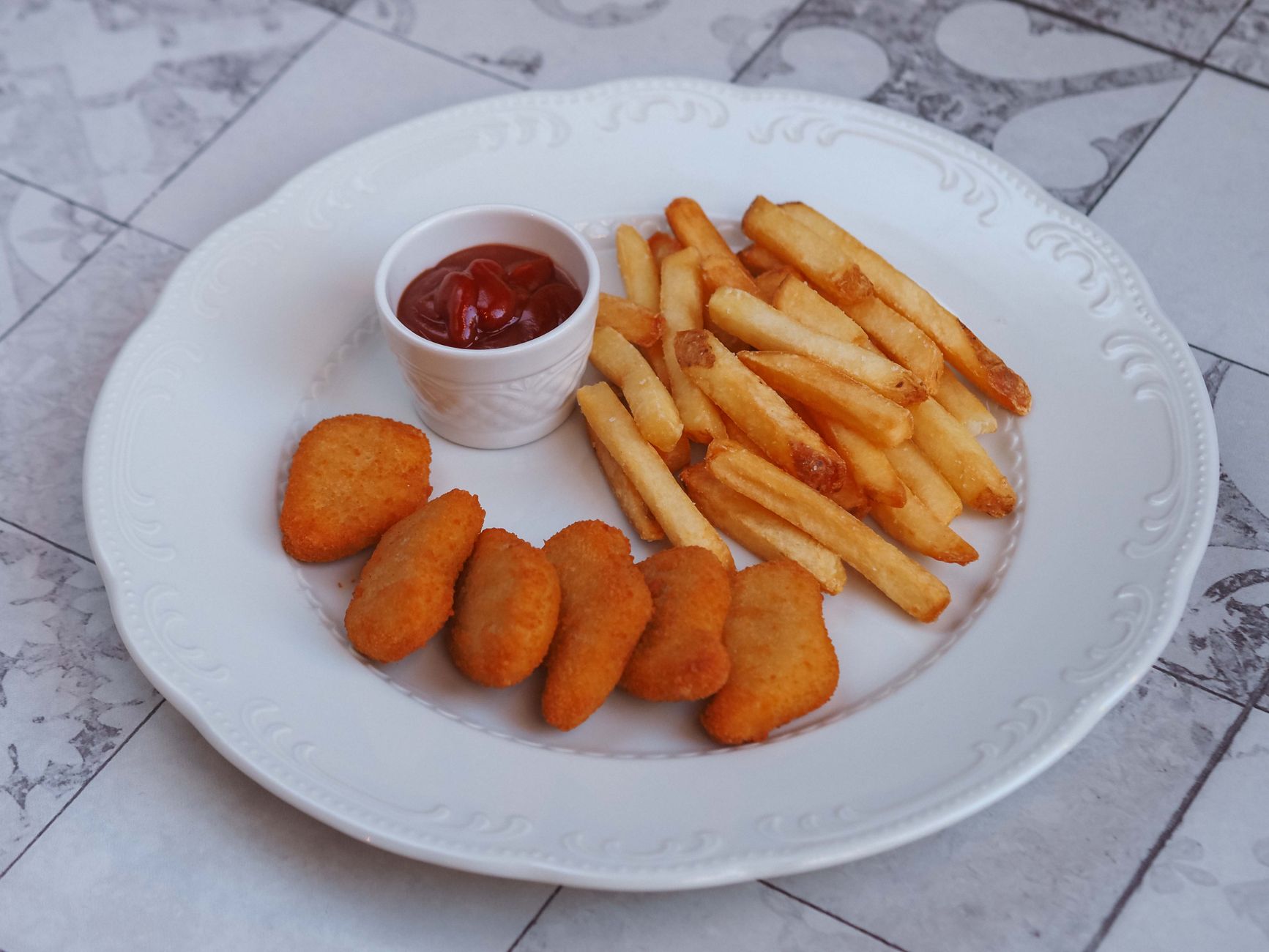 Chicken nuggets and fries on a plate with ketchup
