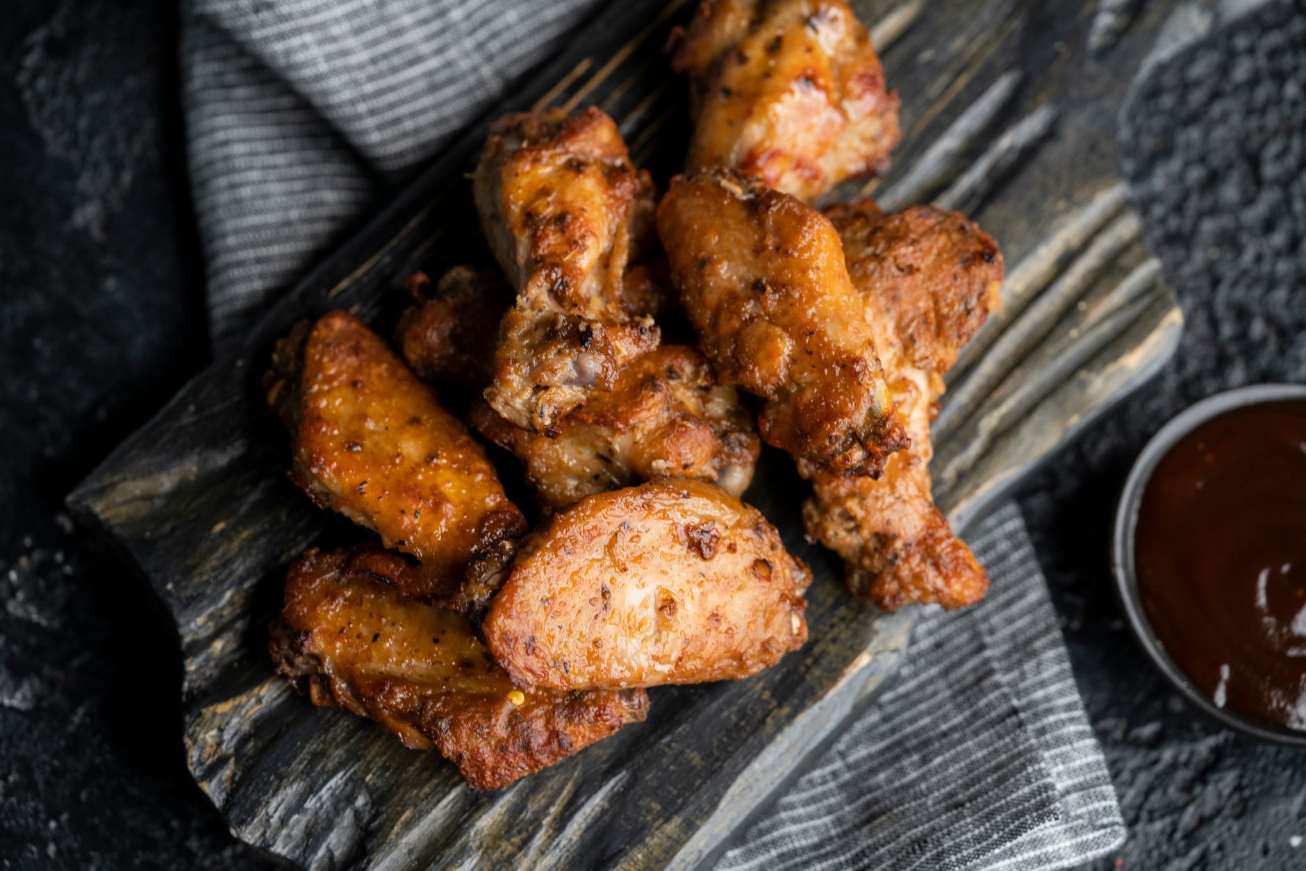 Chicken wings with dipping sauce on a dark serving board